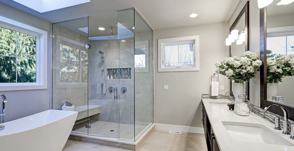 Douche vitrée contemporaine avec porte en verre transparent et cadre chromé installée dans une salle de bain rénovée avec carrelage porcelaine gris clair et robinetterie moderne